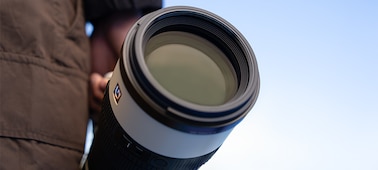 Λήψη ενός φωτογράφου που μεταφέρει τον SEL100400MC, υπό χαμηλή γωνία.